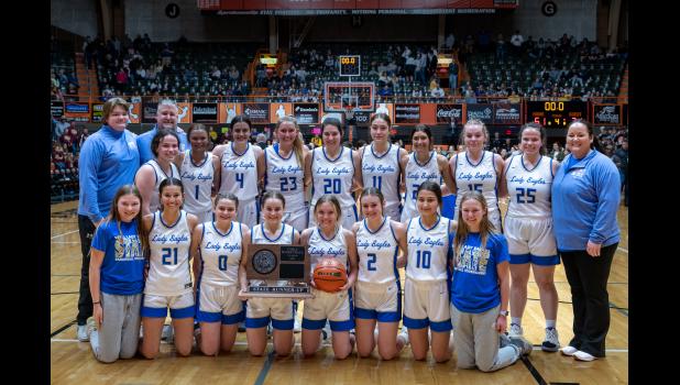 The Wall Eagle basketball team with their State Runner-Up trophy. Back row (left to right): Manager: Dawson Hess, Head Coach: John Hess, Kadence Kusser, Taylor McDonnell, Paige Kjerstad, April Schulz, Skylie Wagner, Rhea Tucker, Alexis Stephen, Faith Frink, Jada Kusser, Assistant Coach: Madison McLaughlin, Bottom Row (left to right): Manager: Brittany Walker, Loucasey Tines, Fallon Ostenson, Nora Dinger, Chloe Fortune, Macee Paulsen, Maranda Poor Bear, and Manager: Karmyn Kjerstad. Photo Courtesy Mama Law Photography