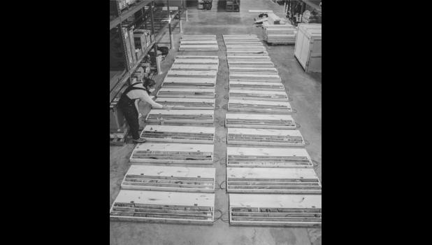 Two columns of core sample boxes are laid on the floor of the warehouse. Megan Smith, an Earth scientist at Lawrence Livermore National Laboratory (LLNL), examines the recently drilled core samples. Each column represents the length of one borehole. Photo by Adam Gomez