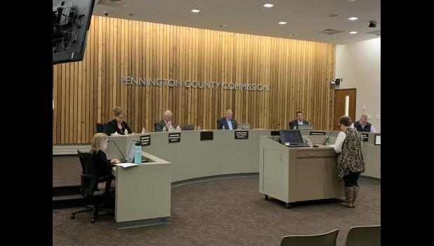 Holli Hennies Commission Manager (standing) goes over the Consent Agenda with the Pennington County Board of Commissioners. The five commissioners seated are Deb Handcock (District 3), Ron Rossknecht (District 1), re-elected Chairman Gary Drewes (District 5), newly elected Vice Chair Lloyd LaCroix (Distict 2), and Travis Lasseter (District 4).