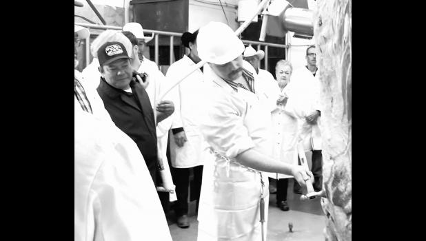 Ken Charfaurous (Left, in a dark shirt) observes as a half of a beef receives the official stamp of approval for the Cooperative Interstate Shipping program. This moment culminates two years of hard work, persistence and patience. Photo courtesy of Elizabeth Meighen